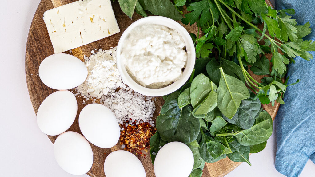 cottage cheese egg bites ingredients with spinach, parsley, basil, eggs, feta, and spices