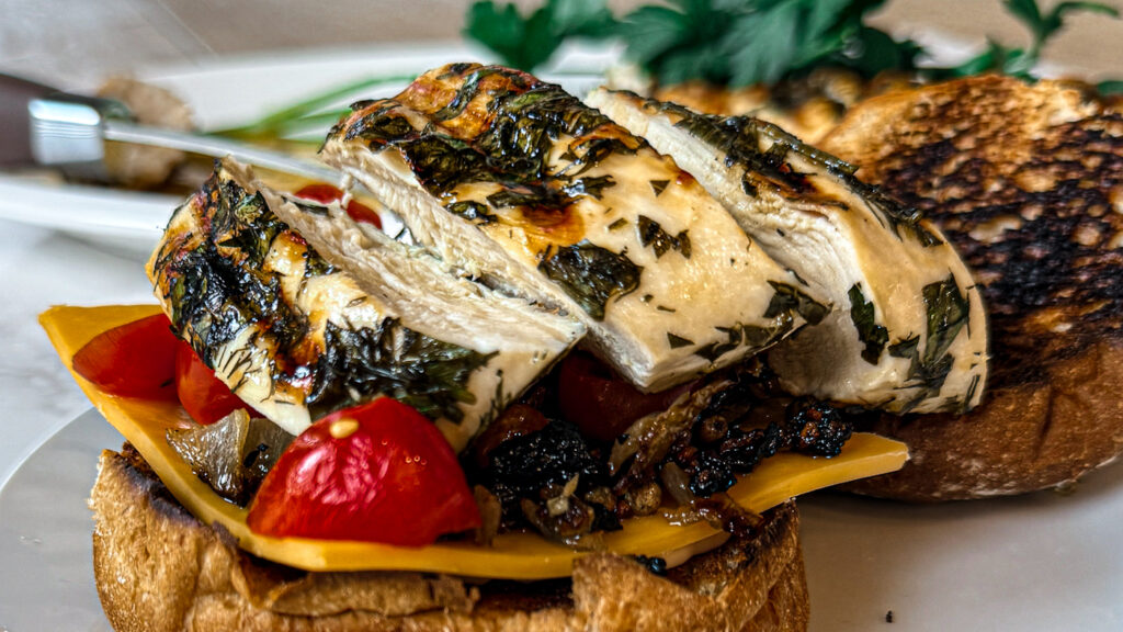 Juicy Lemon Herb Chicken on a multi grain bun with cherry tomatoes, and cheddar cheese