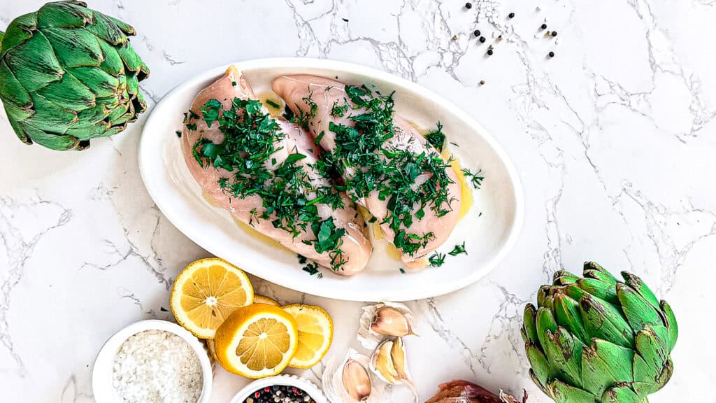 Juicy lemon herb chicken thighs garnished with parsley on a white plate.