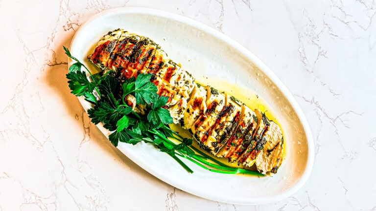 Juicy grilled lemon herb chicken breast with fresh herbs and lemon slices.