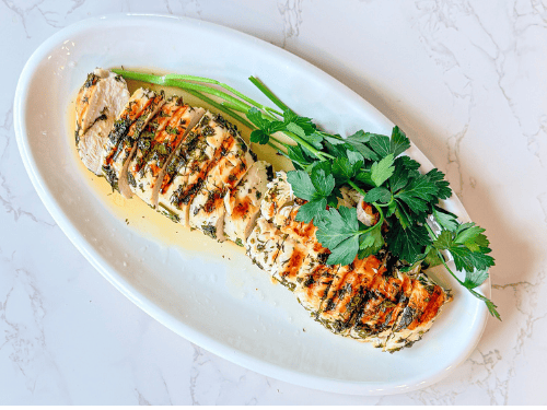 manage the Ozempic gut, lemon-herb chicken in olive oil and lemon juice on a white platter with parsley on a white marble surface