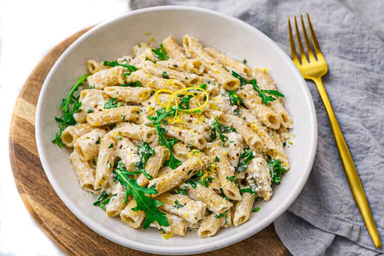 lemon ricotta protein pasta in a white bowl with a gold fork and a blue linen napkin