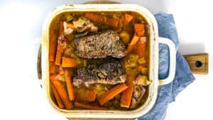 Hearty pot roast with carrots and onions in a baking dish.