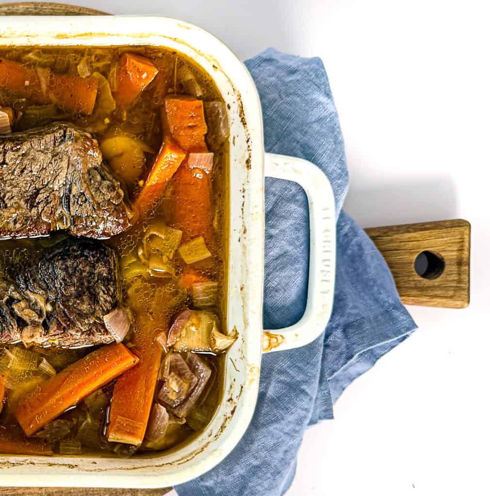 Hearty pot roast with carrots and onions in a baking dish.