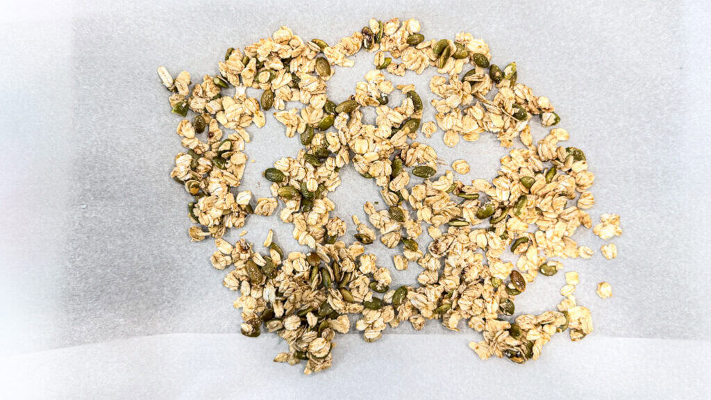 oats, cinnamon, pumpkin seeds in a bowl on a sheet pan