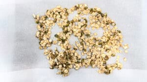 Close-up of homemade olive oil granola clusters on a white surface.