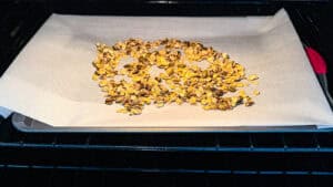 Unbaked homemade olive oil granola on parchment paper in oven.