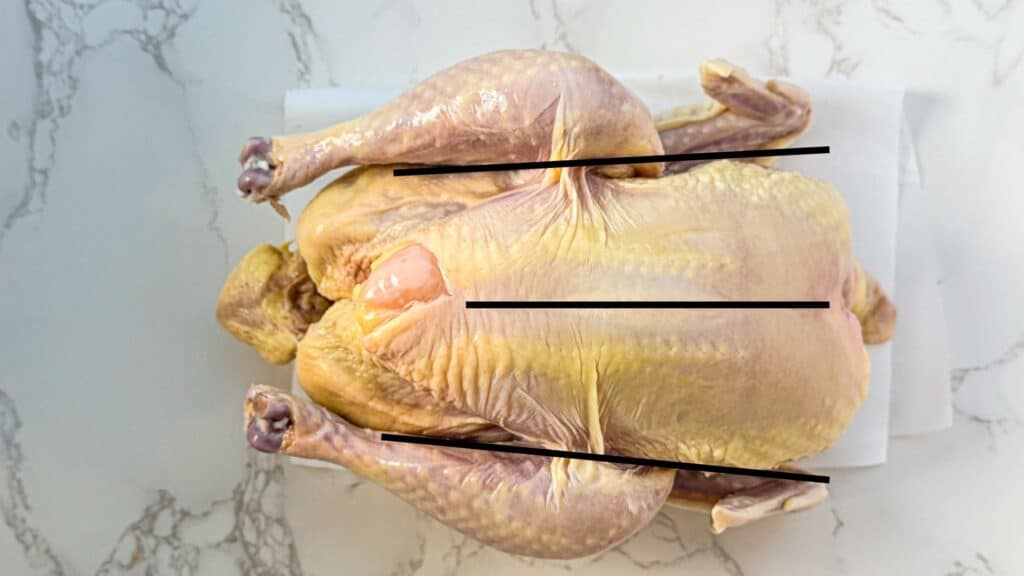 raw chicken sitting on parchment paper on a marble surface
