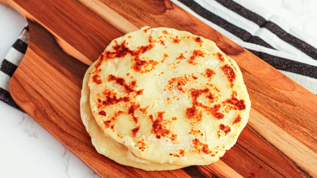 Potato flatbread, homemade, golden-brown, served on a wooden board.
