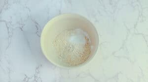 Fresh baking flour in a white bowl on marble surface.