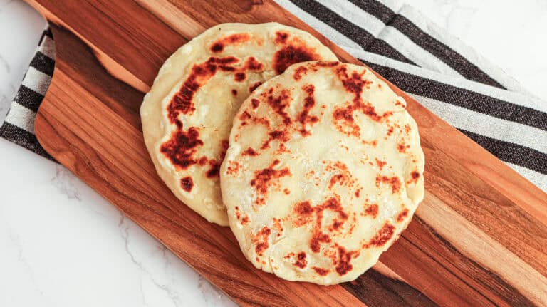 Fresh homemade flatbreads on a wooden serving board.