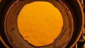 Dough in a cast iron skillet, prepared for baking, showcasing a golden, smooth surface.