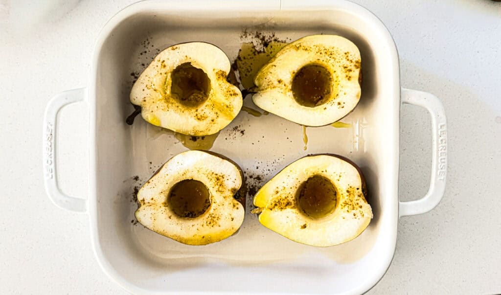  pears halved with olive oil and spices in a white baking dish.