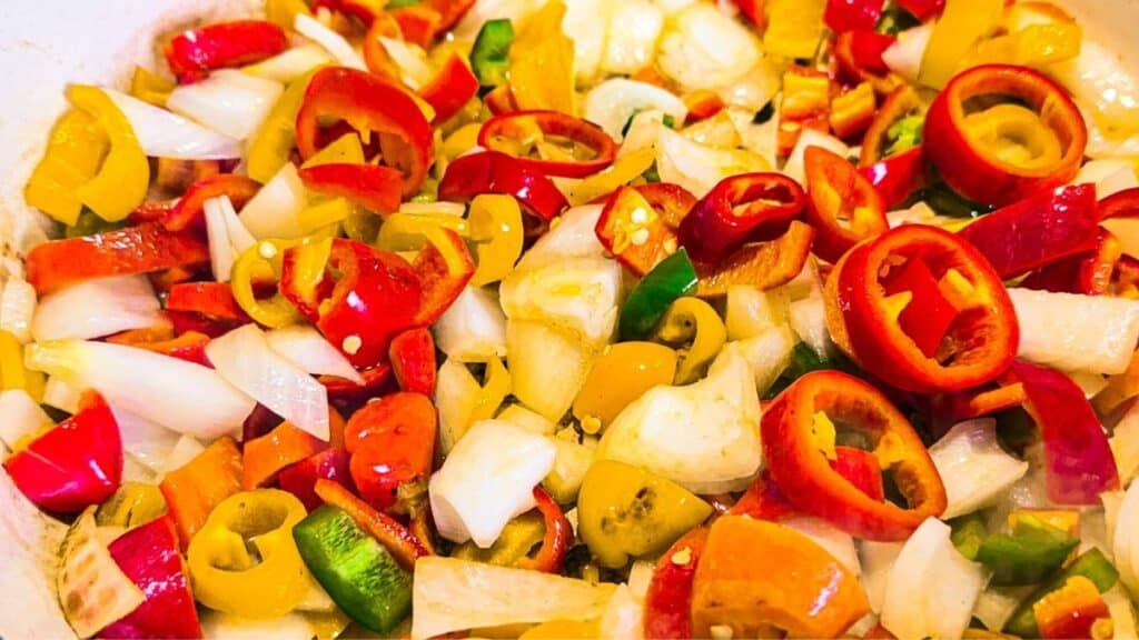 Braised Chicken Sausages with Peppers bell peppers, jalapeno peppers, and onions in a pan