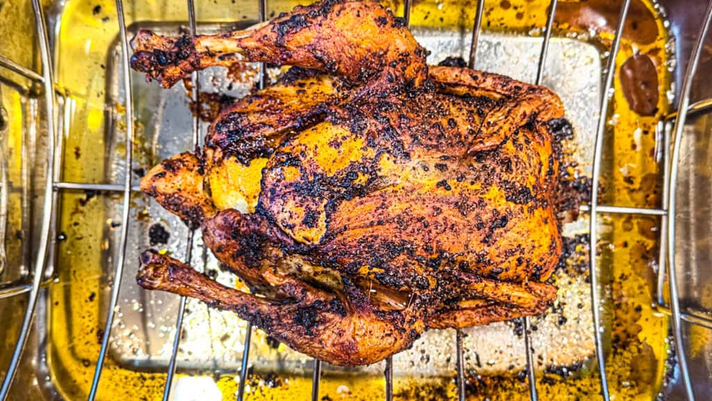 roasted chicken with sumac, lemon zest, paprika, garlic, and olive oil rubbed on it sitting in a metal baking pan.