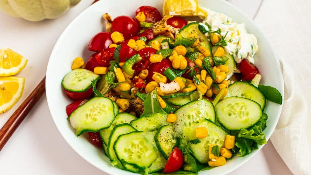 High‑Protein Mediterranean Chicken Flatbread Bowl Fresh cucumber and cherry tomato salad with sweet corn, herbs, and a light dressing.