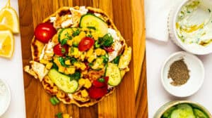 Delicious chicken tacos topped with fresh vegetables, corn, and salsa on a wooden serving board.