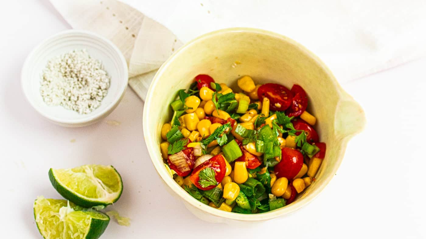 Healthy corn and cherry tomato salad with fresh cilantro in a rustic bowl.