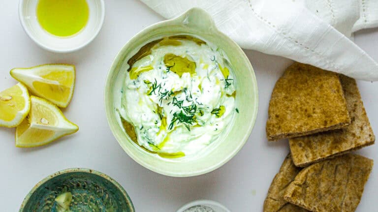 Creamy tzatziki with fresh herbs, served with pita bread and lemon wedges.