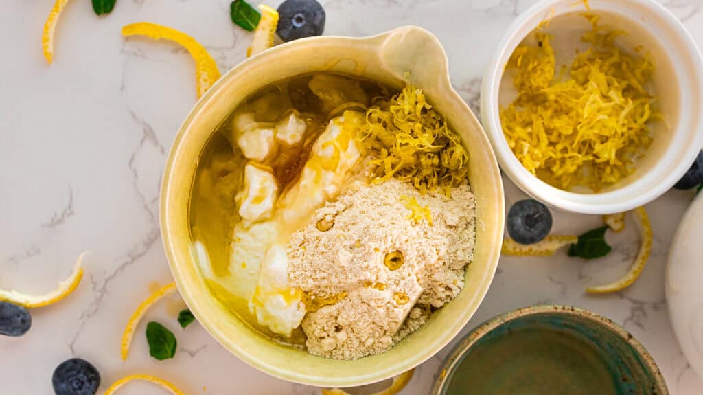 Lemon mousse ingredients in a bow with lemon zest on the side before mixing.