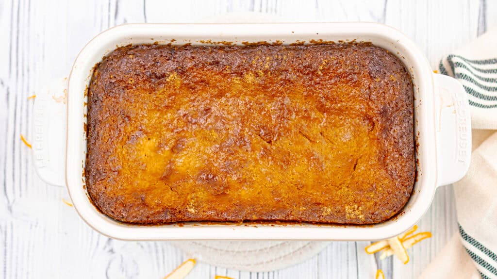 Baked lemon orange olive oil loaf cake in a white baking dish.