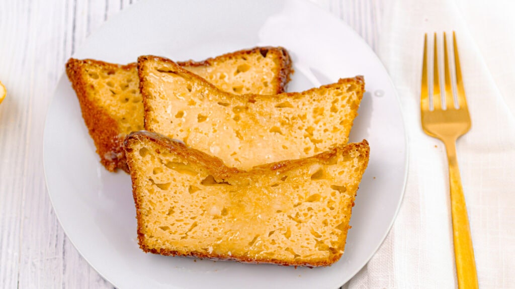 Slices of lemon orange olive oil loaf cake on a white plate.