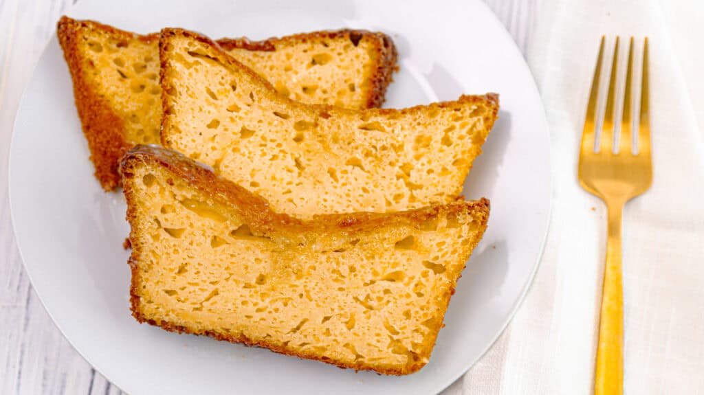 Slices of lemon orange olive oil loaf cake on a white plate with a gold fork.
