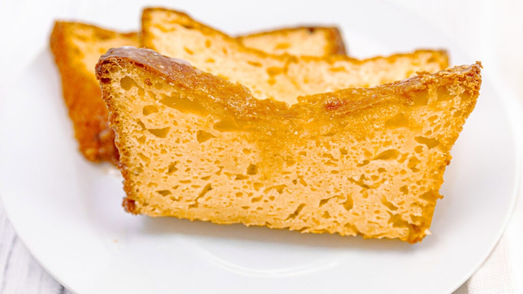 Close-up of lemon orange olive oil loaf cake slice on white plate.
