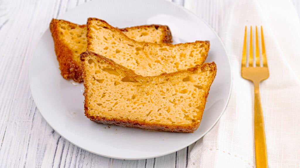 Slices of lemon orange olive oil loaf cake on a white plate with a gold fork.