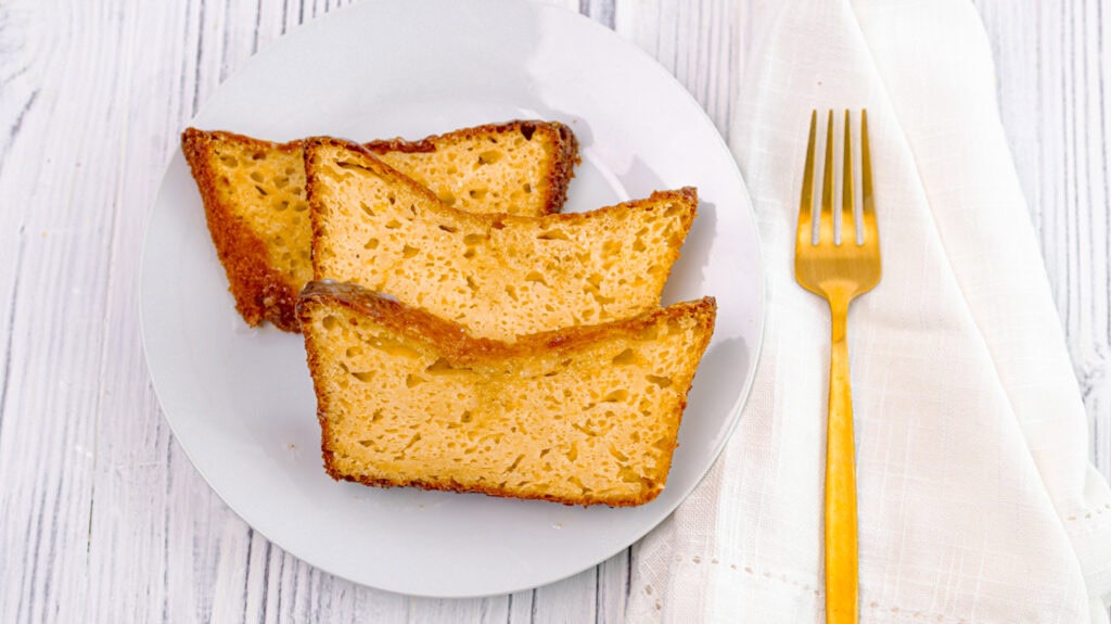 Slices of lemon orange olive oil loaf cake on a white plate with a gold fork.