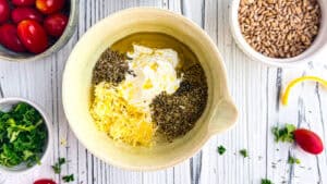 Herb and lemon butter mixture in a bowl with fresh ingredients around.
