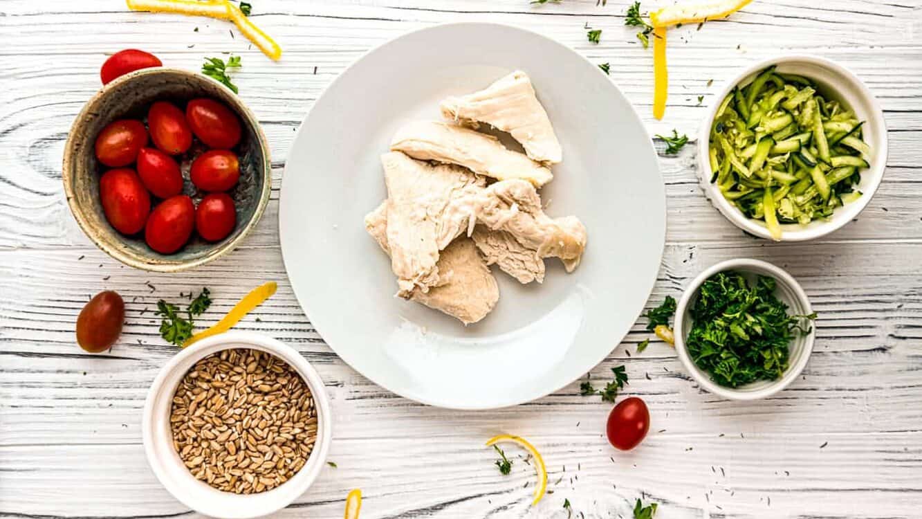 Mediterranean chicken bowl ingredient flatlay with chicken tomatoes, parsley, spices, 