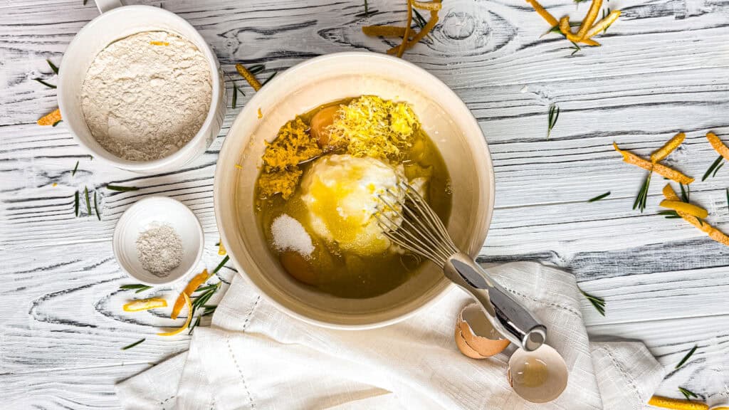 A ceramic bowl with olive oil cake ingredients