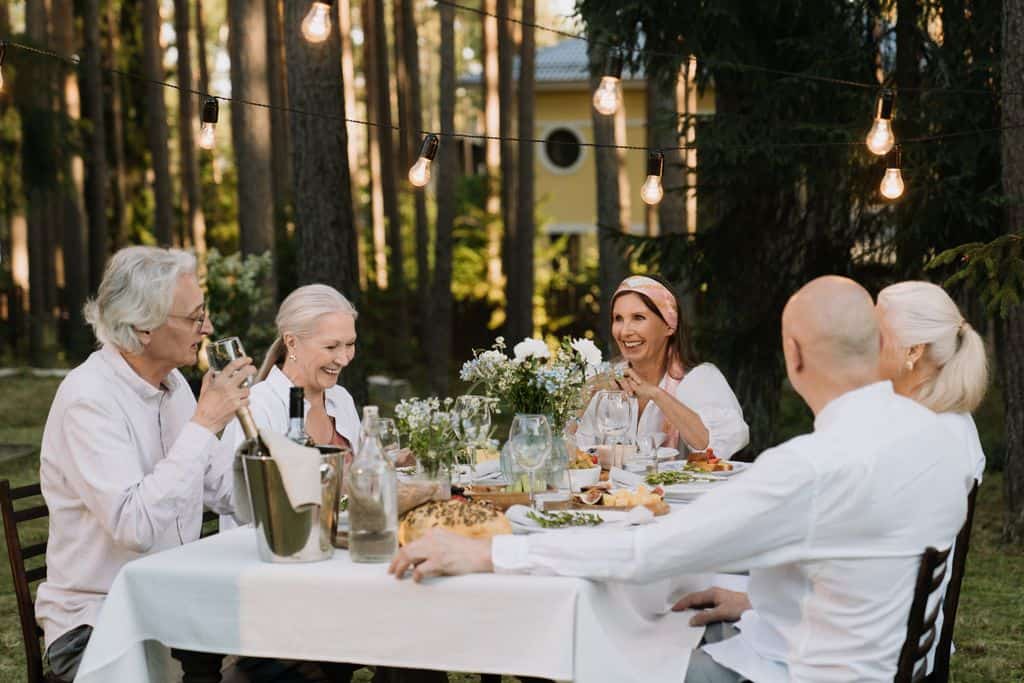 Senior group enjoying a delightful outdoor dinner party with laughter and wine. The Mediterranean Diet for GLP-1 Nausea