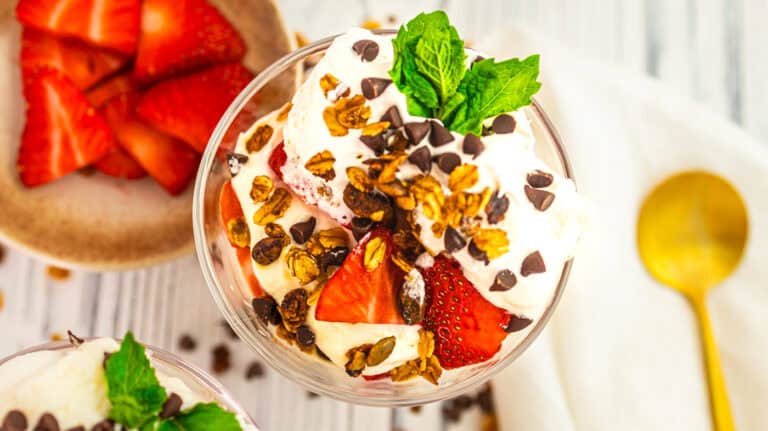 Delicious parfait with strawberries, whipped cream, chocolate chips, and mint.