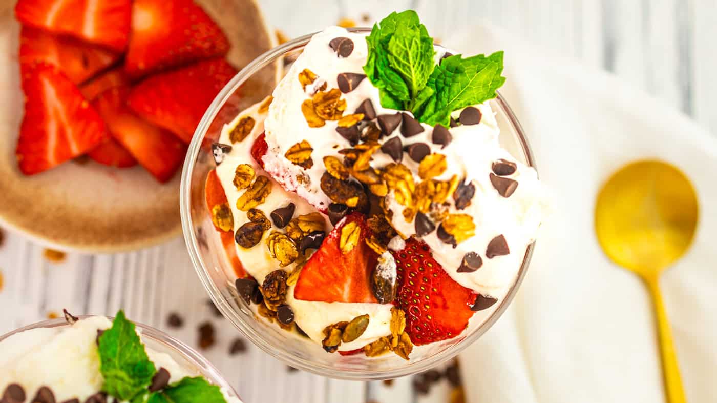 Delicious parfait with strawberries, whipped cream, chocolate chips, and mint.