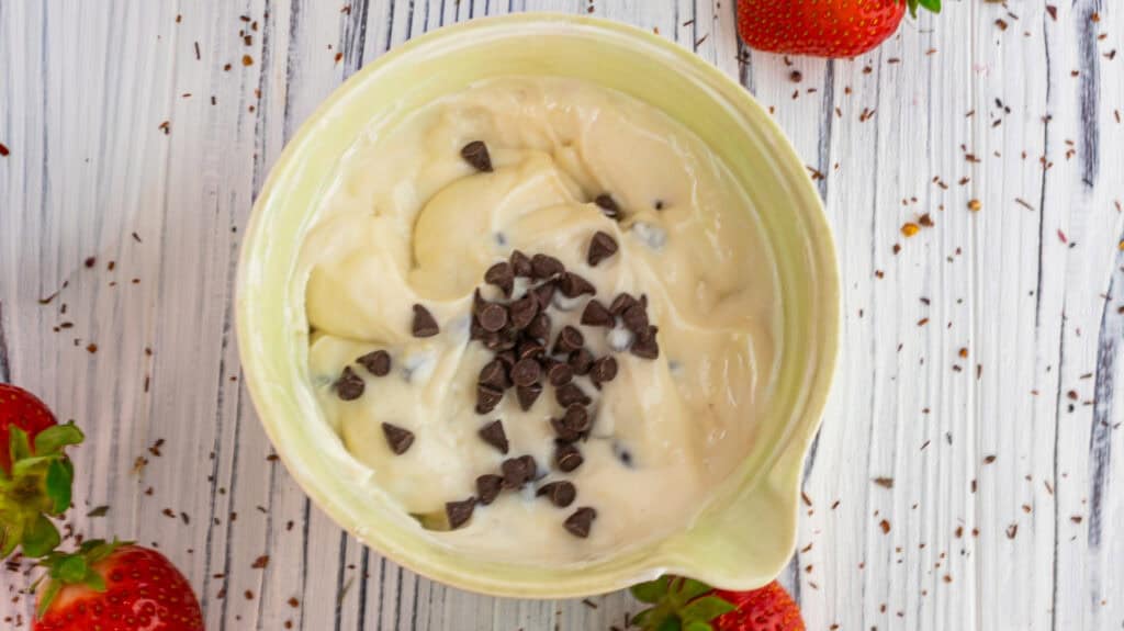 Creamy vanilla and strawberry parfait with chocolate chips in a bowl.