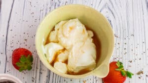 Creamy vanilla ice cream served in a bowl with fresh strawberries nearby.