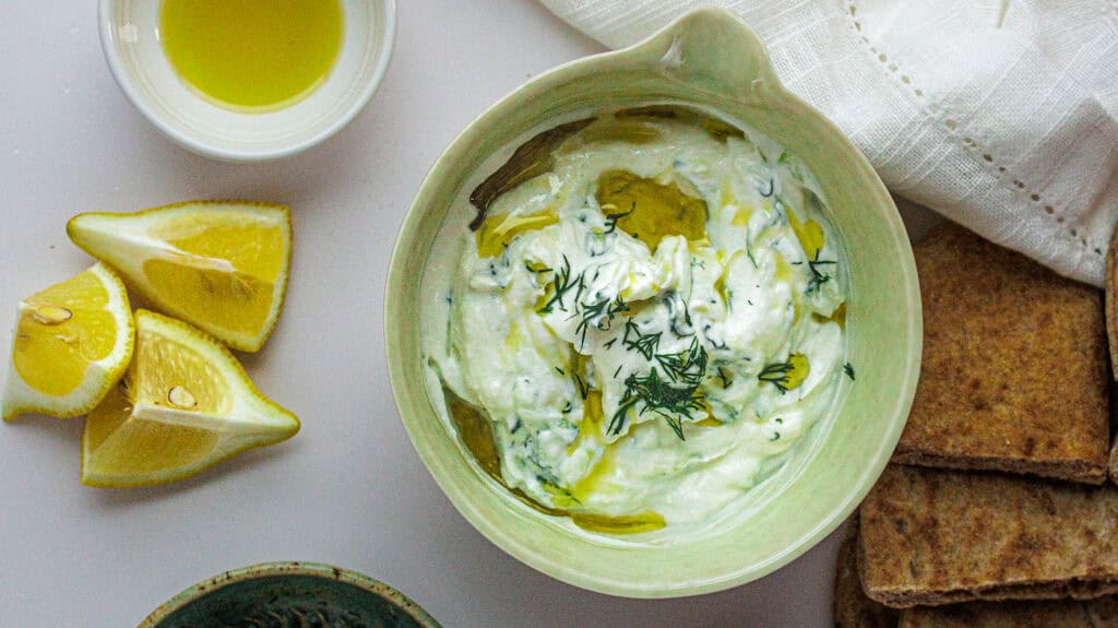 Fresh Greek tzatziki with lemon wedges and bread, perfect for Mediterranean cuisine lovers.