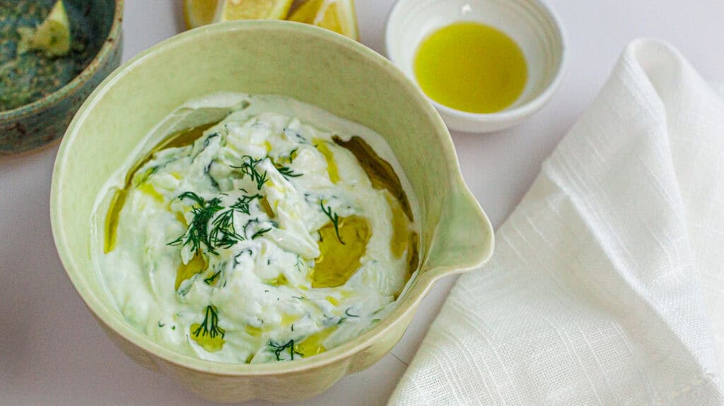 Traditional Greek Tzatziki sauce with dill, olive oil, and creamy yogurt in a bowl.