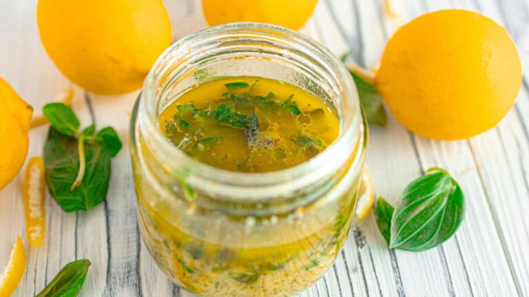 lemon-orange herb dressing surrounded by lemons and basil