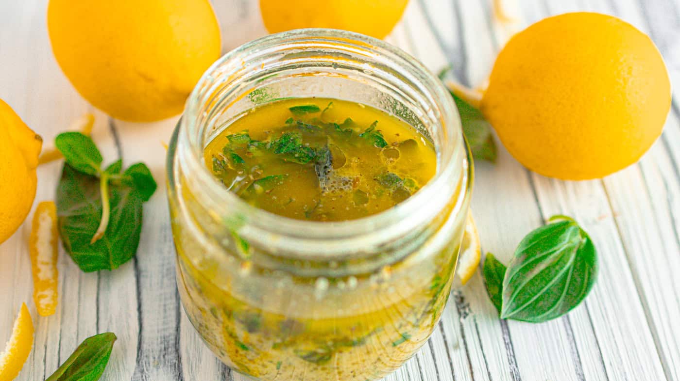lemon-orange herb dressing surrounded by lemons and basil